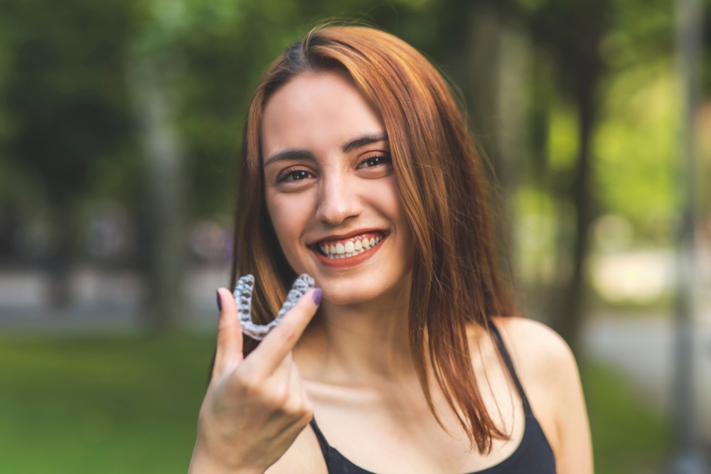 young teen smiling and holding invisalign aligner